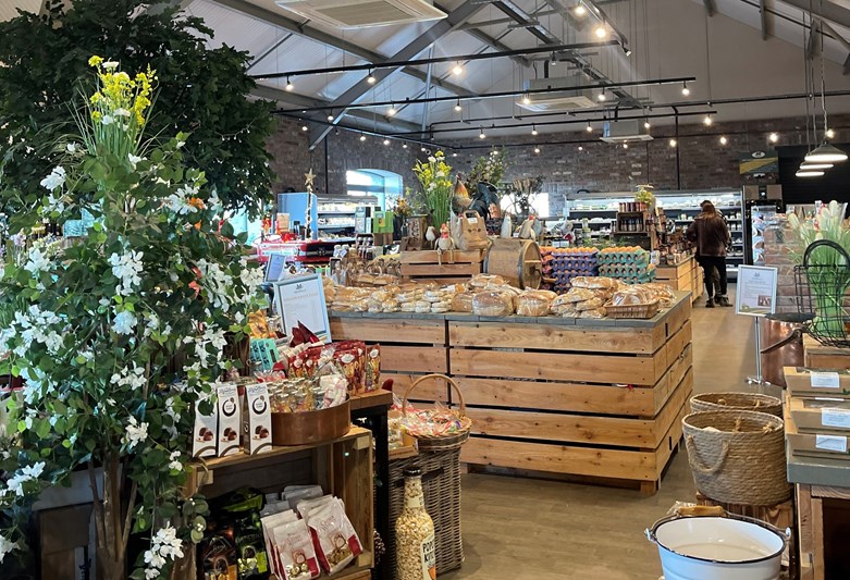 Interior of a farm shop. Food displayed on shelves and plants.