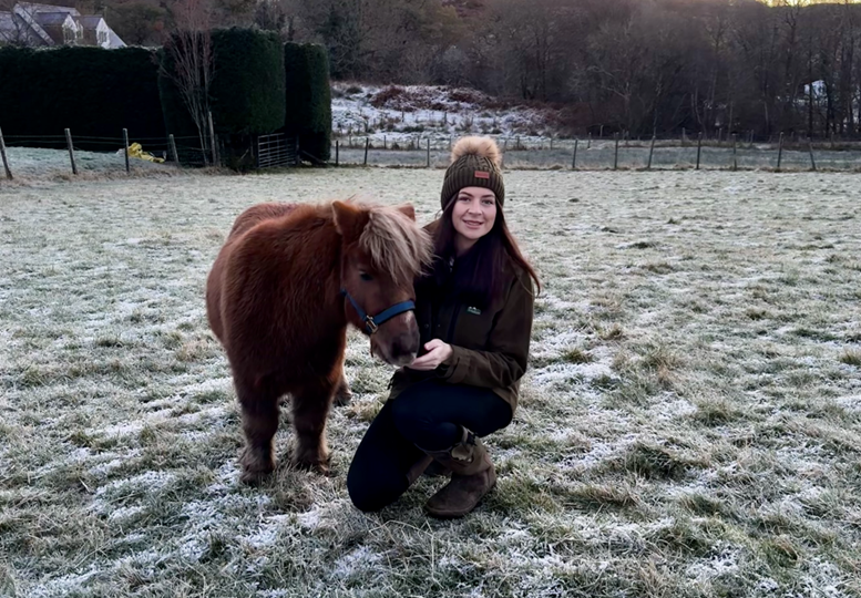 A young woman on a farm in winter, with a Shetland pony.