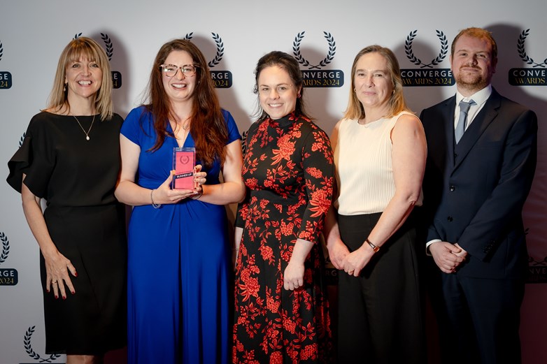 Five people pose for a photo, holding an award.